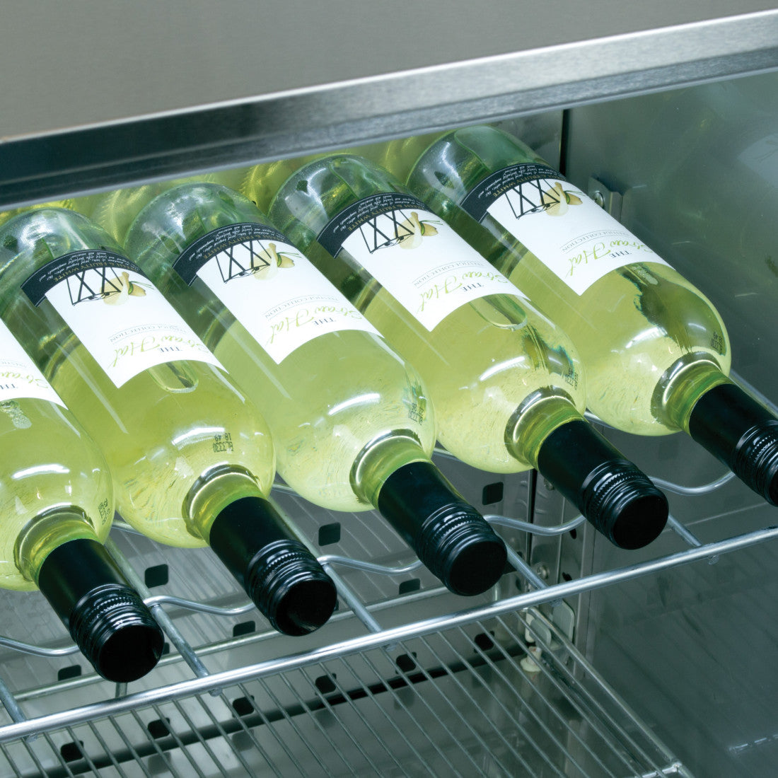 Interior view of the Prodis bottle cooler showing wine bottles stored horizontally on chrome shelves for even cooling and easy access
