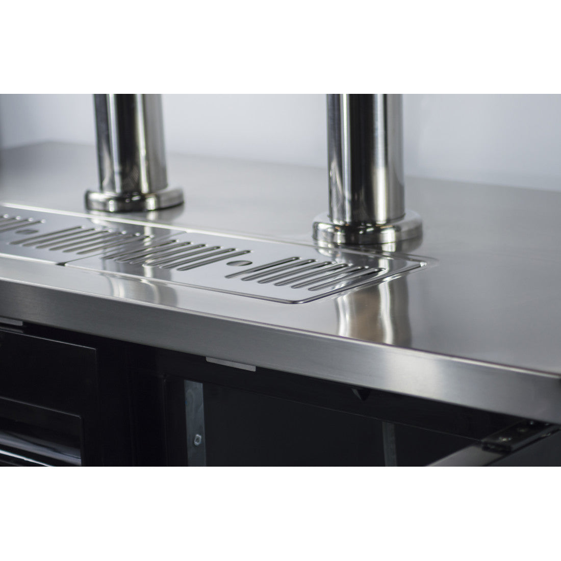 Close-up of the stainless steel drip tray on the Prodis double tap keg cooler, designed for clean pouring above a wheeled cabinet base