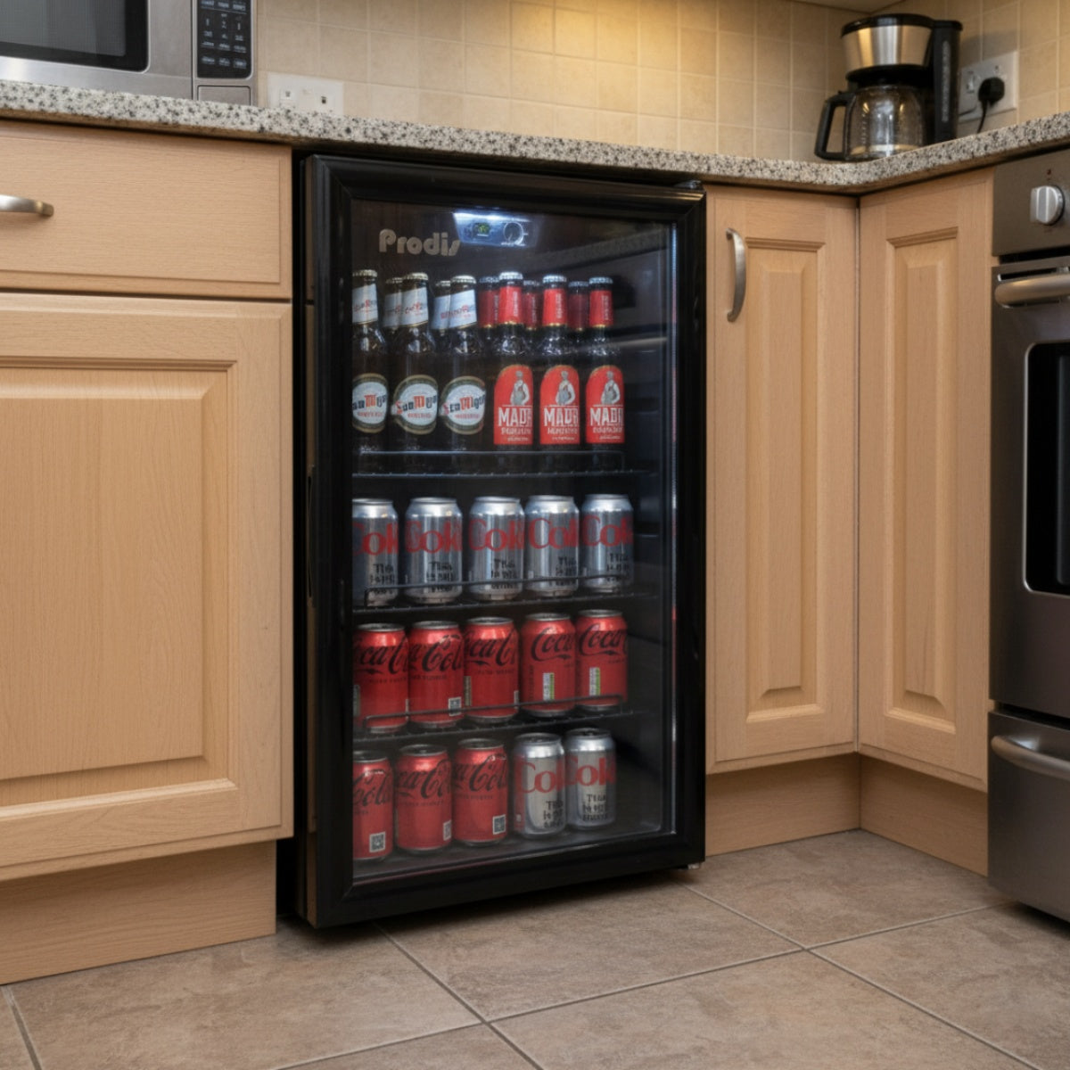 Lifestyle view of the Prodis under counter beverage cooler fitted into a kitchen, showing seamless integration beneath worktops with chilled drinks on display